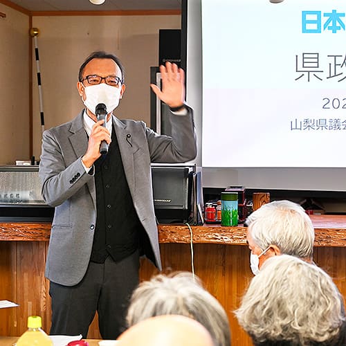 会場でマイクを使って活動を報告する様子