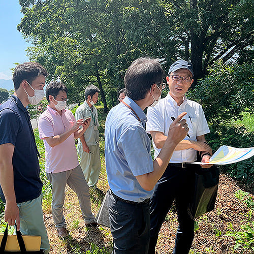 屋外の現地視察で資料を確認する様子